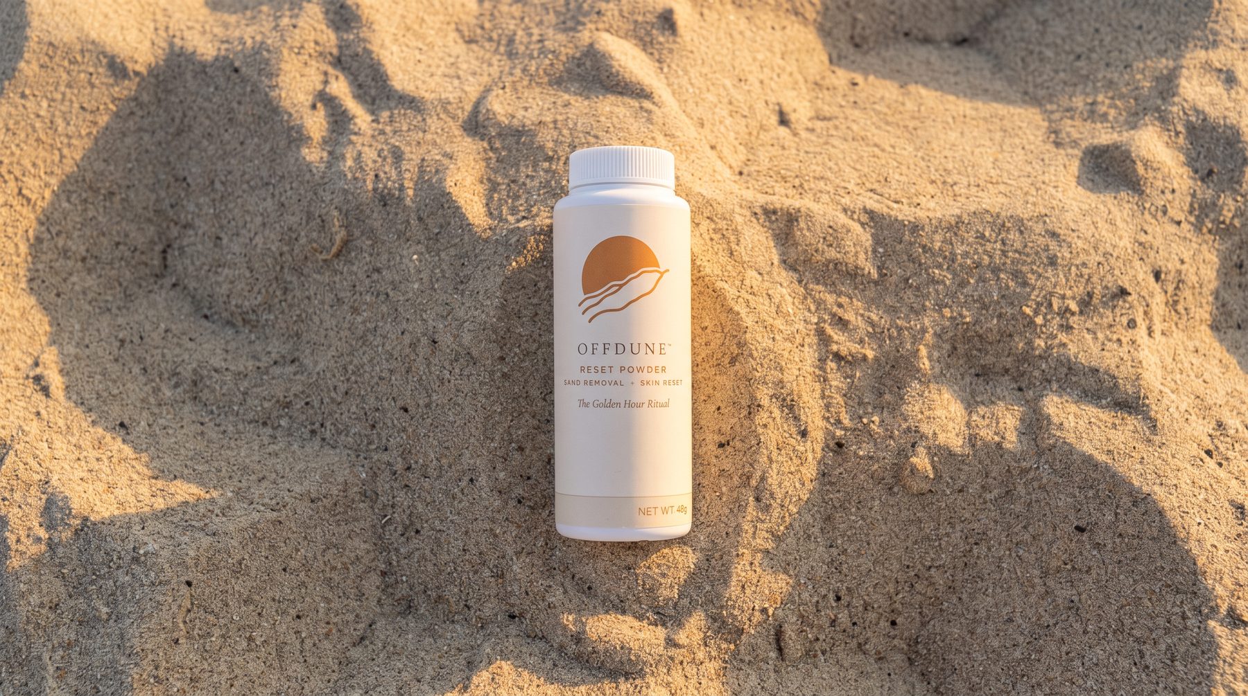 OFFDUNE Reset Powder bottle lying in warm, late-day beach sand, seen from above